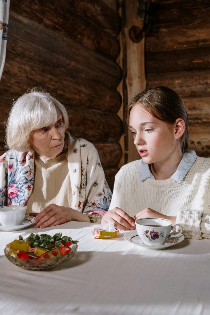 A touching moment between a grandmother and granddaughter sharing tea indoors.