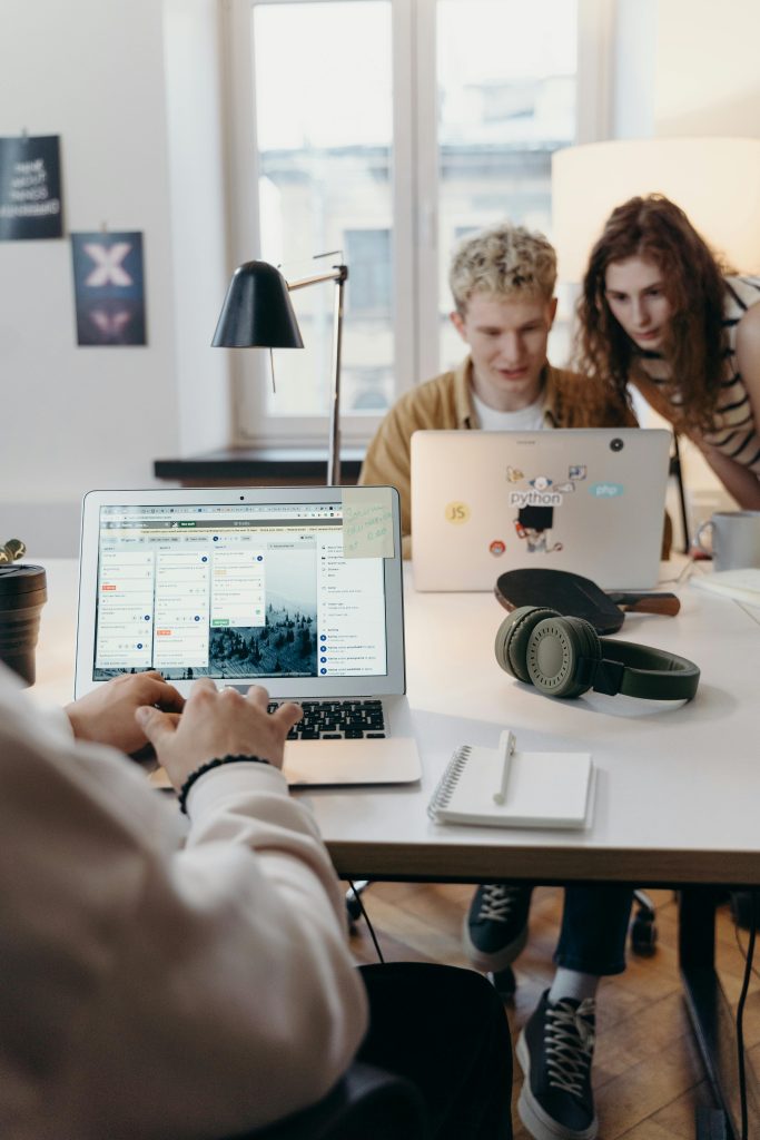 Young team collaborating at a modern workspace with laptops and headphones.